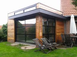 Exemple d'extension contemporaine avec menuiseries aluminium, bardage en mélèze et toiture terrasse